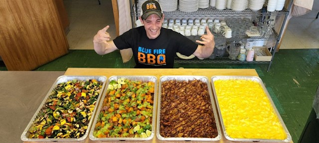 Matt Simpson posing with trays of food